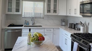 A modern kitchen with white cabinets, a marble countertop, and stainless steel appliances. - Classy 4-bedroom house with AC in Redondo Beach (Redondo Beach)