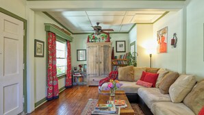 A cozy living room with a sofa, a coffee table with magazines, a wooden cabinet, and a ceiling fan. - Charming Arroyo Cottage walking distance from Old Town Arroyo (Arroyo Grande)