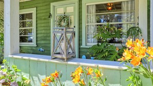 A green house with a porch, a lantern, and flowers. - Charming Arroyo Cottage walking distance from Old Town Arroyo (Arroyo Grande)