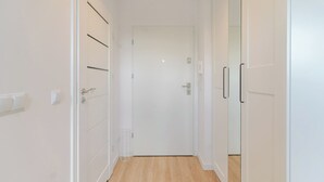 A narrow hallway with white walls and wooden flooring. - Chopina Comfort Studio (Katowice)