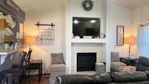 A living room with a fireplace, a television, and a ceiling fan. - Soothing 4-bedroom house with AC in charming Fountain (Fountain)