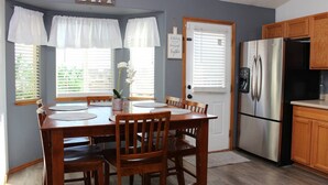 A kitchen with a dining table, chairs, a refrigerator, and a door with a sign. - Soothing 4-bedroom house with AC in charming Fountain (Fountain)
