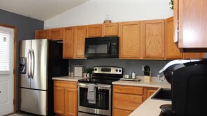 A modern kitchen with wooden cabinets, stainless steel appliances, and a central island. - Soothing 4-bedroom house with AC in charming Fountain (Fountain)