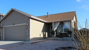 A single-story house with a garage, a front porch with a bench, and a gravel driveway. - Soothing 4-bedroom house with AC in charming Fountain (Fountain)
