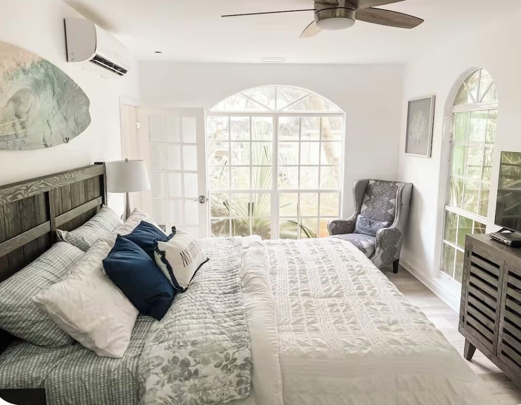 Un dormitorio con una cama grande, una silla, un televisor y una ventana con vistas.