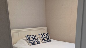 A bedroom with a bed, white bedding, patterned pillows, and a ceiling fan. - Lovely 4-bedroom mobile home in Oak Island 6 MIN WALK TO BEACH (Oak Island)
