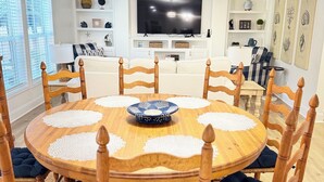 Une salle à manger avec une table ronde en bois, huit chaises et un lustre.