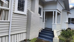 A two-story house with a front porch, a set of stairs leading to the entrance, and a small garden area. - 5 Bedroom House, 7 Rangiatea Road, Epsom, Auckland (Auckland)