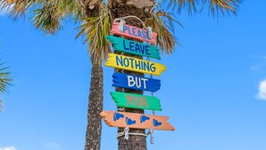 A palm tree with colorful signs that read "PLEASE LEAVE NOTHING BUT YOUR FOOTPRINTS."