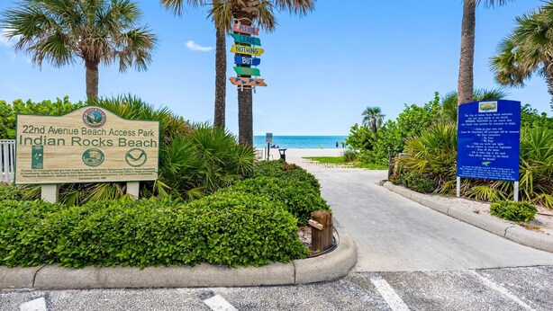 A sign for 22nd Avenue Beach Access Park Indian Rocks Beach with a beach view in the background.