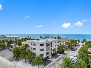 Un hôtel à plusieurs étages doté d’un parking, entouré de palmiers et offrant une vue sur l’océan.