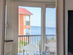 Un balcón con vista al mar y un edificio de techo rojo.