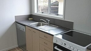A compact kitchen with a dishwasher, a double sink, and a stove. - 3 Bedroom House A, 23 Mallard Drive, Rotorua (Rotorua)