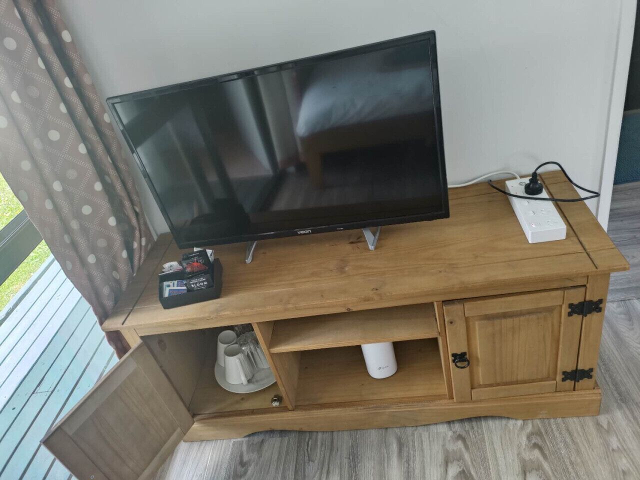 Un mueble de televisión de madera con un televisor de pantalla plana, un control remoto y una regleta de enchufes.