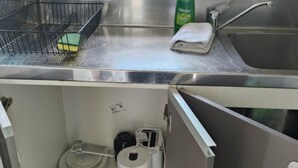 A compact kitchen with a stainless steel sink, a dish rack, a bottle of dish soap, and a towel. Below the sink, there are a coffee maker, a toaster, and a plate rack. - 2 double beds including 1 double sofa bed Garden Chalet, 7 Rangiatea Road, Epsom, Auckland (Auckland)