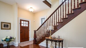 A wooden staircase with a handrail, a door with a window, and a wall-mounted light fixture.