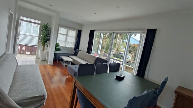 Un vaste espace de vie comprenant un canapé, une table à manger et des chaises. Un balcon offre une vue sur l’extérieur.