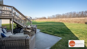 A covered outdoor seating area with a sofa, fire pit, and logs. - Deer Haven in Georgetown Township (Jenison)