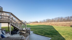A covered outdoor seating area with a sofa, fire pit, and logs.