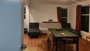 Een kamer met een bank, een eettafel en een raam met gordijnen.