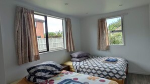 A bedroom with two beds, large windows, and a view of the outside. - 6 Beds including 4 Double Beds and 2 Sofa Bed Garden Chalet, 8 Renton Road, Mt Albert, Auckland (Auckland)
