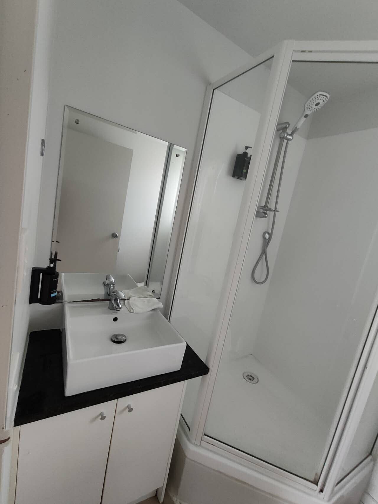 A bathroom with a white sink, mirror, and shower enclosure.