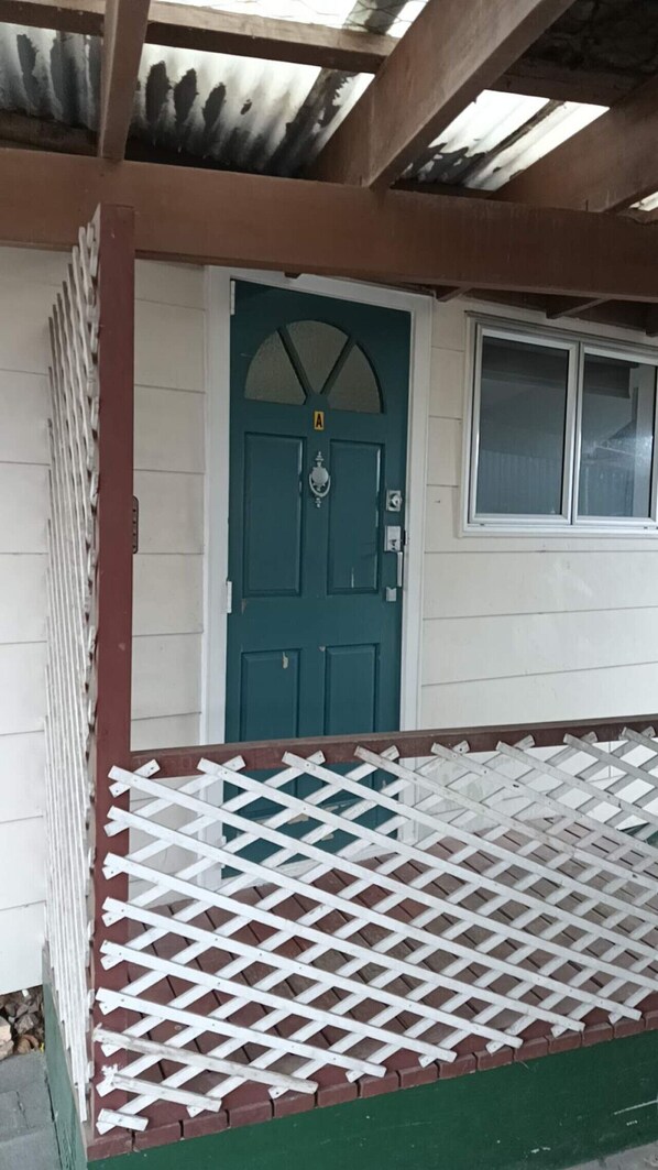 Een huis met een groene deur, een wit raam en een wit hekwerk.