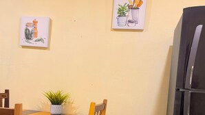 A kitchen with a wooden table, chairs, a refrigerator, and two wall-mounted paintings. - 10 Coleguita in Isla Mujeres (Isla Mujeres)