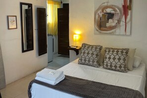 A hotel room with a bed, a bedside lamp, a mirror, and a painting on the wall. - 05 Conchi Abajo in Isla Mujeres (Isla Mujeres)