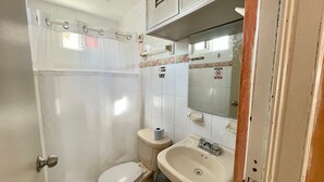 Casa de banho pequena com sanita, lavatório e cortina de chuveiro.