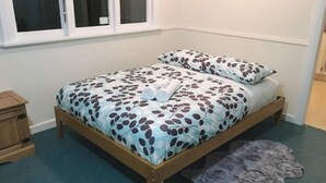 A bedroom with a bed, pillows, a small wooden nightstand, and a window. - 4 Beds including 2 Double Beds and 2 Sofa Beds up to 8 People, House, 22B Pererika St, Rotorua (Rotorua)