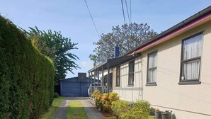 A pathway leading to a building with a covered porch and potted plants. - 5 Bedroom House at Rotorua (Rotorua)