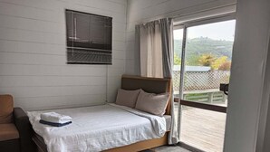 A bedroom with a bed, a chair, a window with blinds, and a view of the outdoors. - 5 Bedroom House at Rotorua (Rotorua)