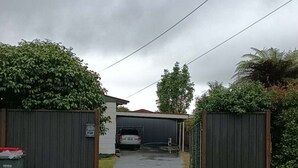 A residential driveway leading to a garage under a bridge. - 3 Beds including 1 Double Bed, 2 Single Sofa Beds Garden Chalet, Unit C, 9 Steeles Lane (Rotorua)