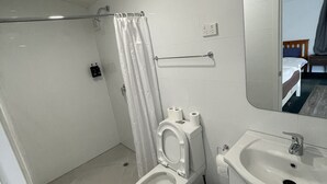 A modern bathroom with a toilet, shower, and sink. - 1 Double and 1 single Bed unit B (Rotorua)