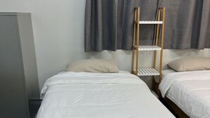 En enkeltseng med en træstige, hvide sengetøj og et foldet håndklæde.