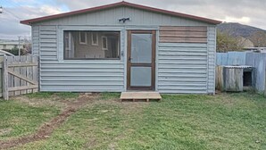 A small, single-story building with a red roof, a front door, and a window. - 4 double and 2 Sofa Beds chalet (Rotorua)