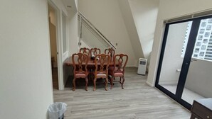 Een eethoek met een houten tafel en stoelen, een prullenbak en een schuifdeur naar een balkon.