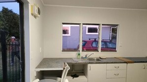 A compact kitchen with a window, a sink, and a small dining area. - 3 Bedroom Small House B (Auckland)