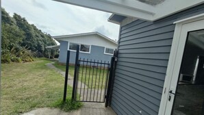 A residential property with a garage door, a concrete driveway, and a grassy yard. - 3 Bedroom Small House B (Auckland)