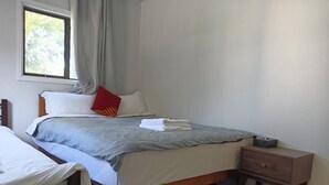 Un dormitorio ordenado con cama, mesita de noche y ventana.