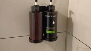 Deux distributeurs de gel douche fixés sur un mur carrelé.