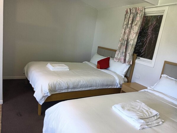 A double room with two beds, each with white linens and a red pillow.