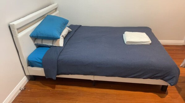 A bed with a white headboard, blue bedding, and a folded white towel on the footboard.