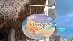 Une enseigne indiquant l’emplacement du club de plage de Mango, avec les coordonnées et l’adresse.