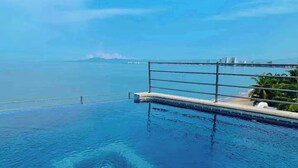 Une piscine avec vue sur la mer et les bâtiments situés au loin.