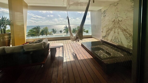 Un balcon avec un hamac, un jacuzzi et une vue sur la mer.