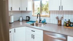 A modern kitchen with white cabinets, a stainless steel sink, and a window providing natural light. - Spacious & Cozy Home near Olde Town Arvada (Arvada)