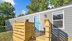 A mobile home with a wooden deck, a blue door, and a window with a screen. - Villa Slate Coastal Country Retreat PCS • Nurses • Contractors- Weekly & Monthly (Jacksonville)