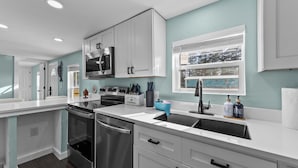 A modern kitchen with white cabinets, stainless steel appliances, and a window with a view. - Villa Slate Coastal Country Retreat PCS • Nurses • Contractors- Weekly & Monthly (Jacksonville)